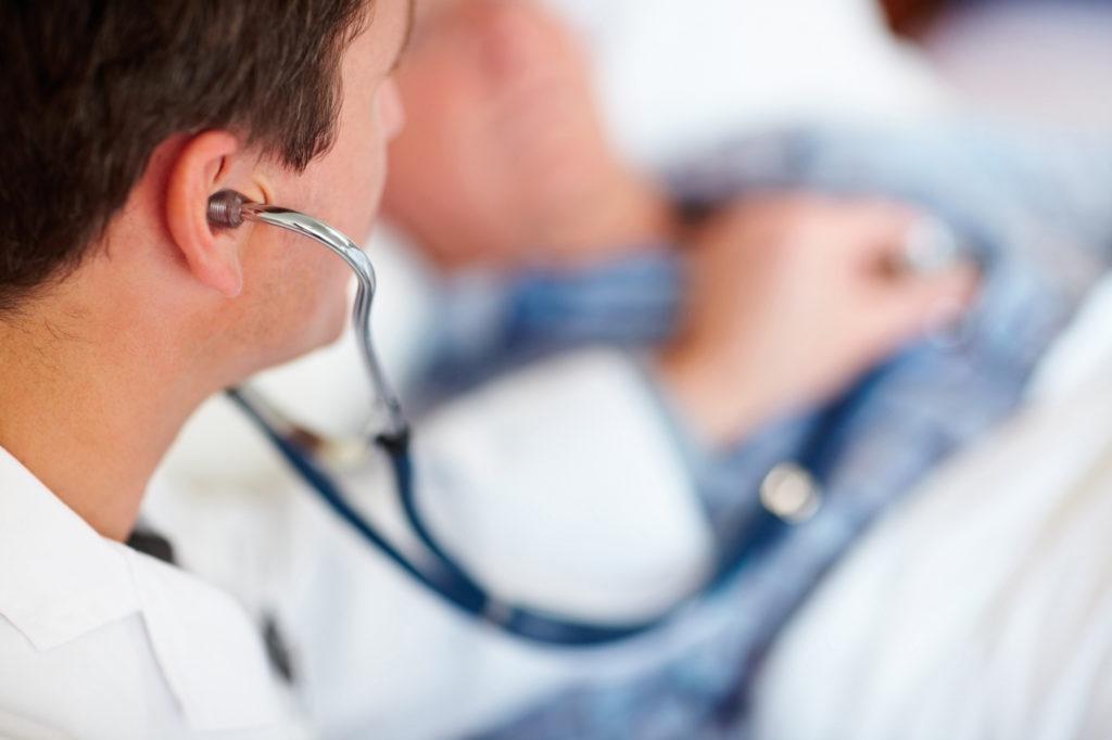Doctor examining a patients heart beat with a stethoscope.