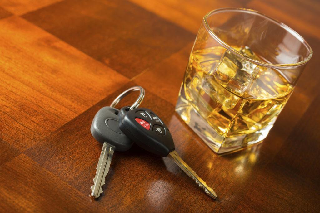 Filled whiskey glass setting beside car keys.